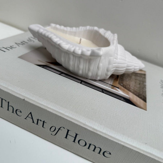 White shell on top of a book titled 'The Art of Home'.
