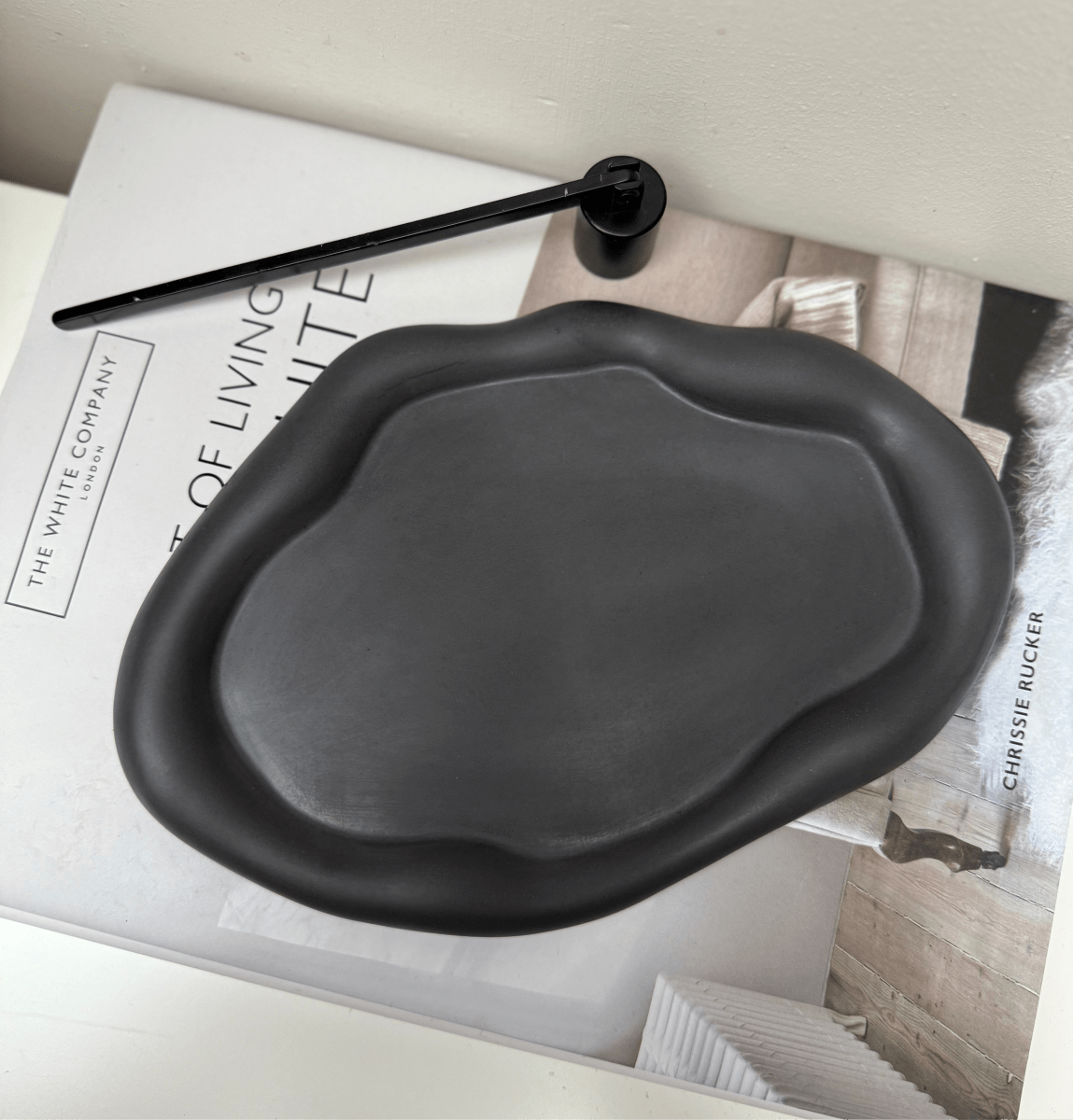 Black ceramic dish on a magazine with a minimal background