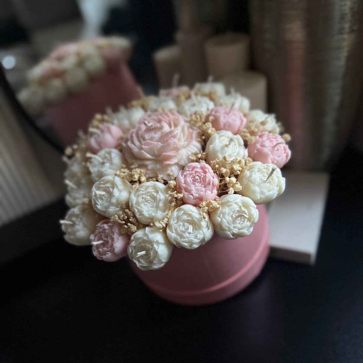 Pink and white flower arrangement in a pink pot on a dark surface.
