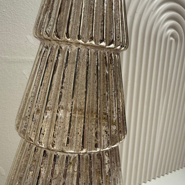 Decorative metallic glass tree with a textured surface against a neutral background