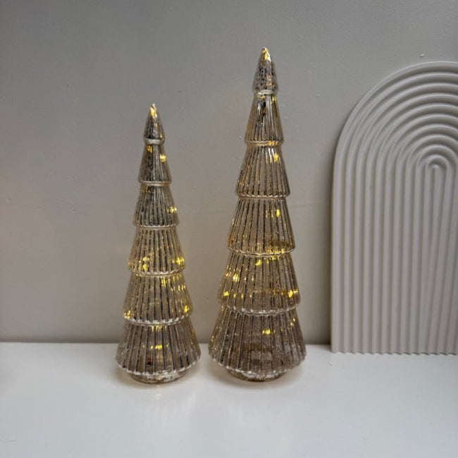 Two decorative cone-shaped trees with LED lights on a plain surface.