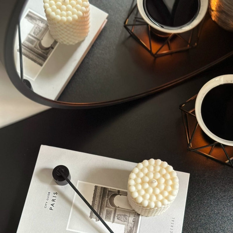 Oval bubble candle placed on top of a Paris book, Mirror and glowing wax burner