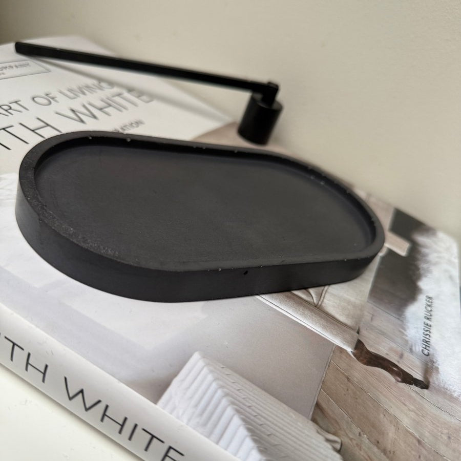 Black oval Decorative tray on top of a book titled 'White' by Chrissie Bucker.