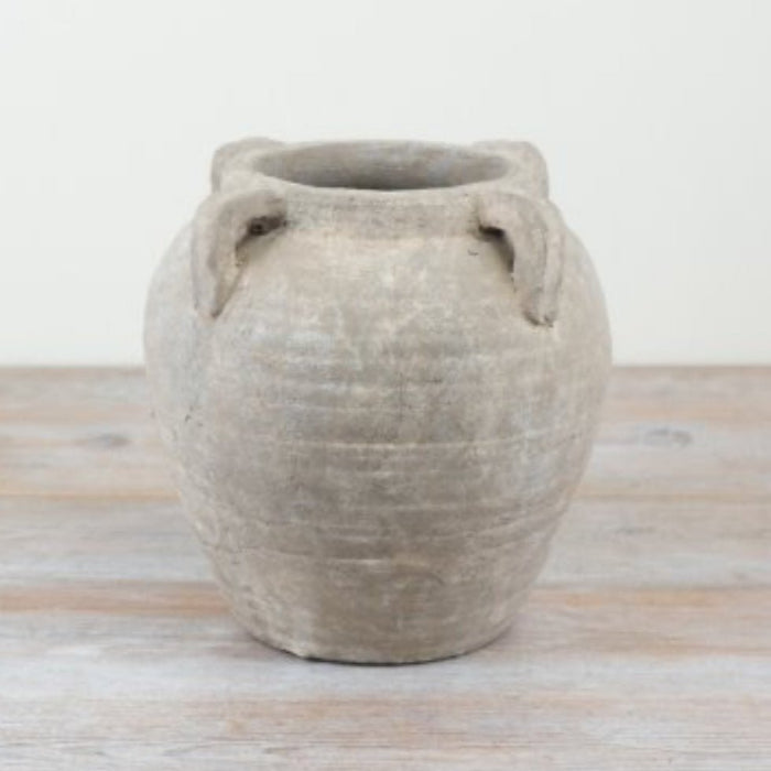 Textured ceramic pot on a wooden surface with a light background