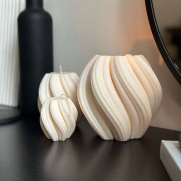 Three spherical candles with wavy patterns on a dark surface.