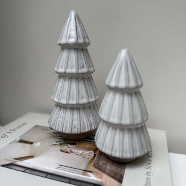 Two Gray Reactive Glaze Christmas Tree figurines on a magazine with a plain background