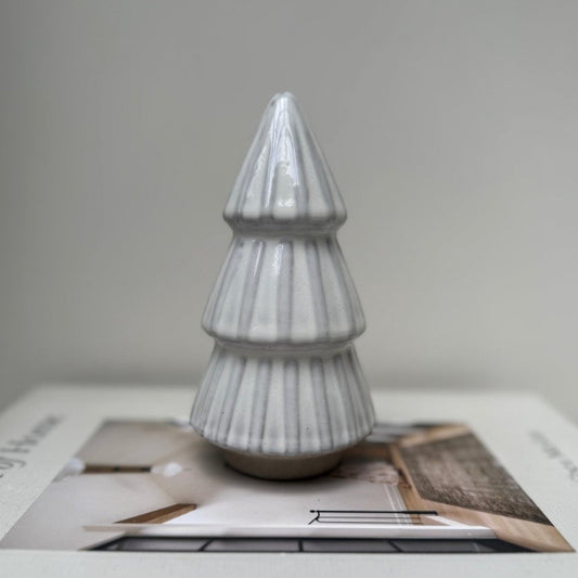 Ceramic Christmas tree ornament on a magazine with a plain background