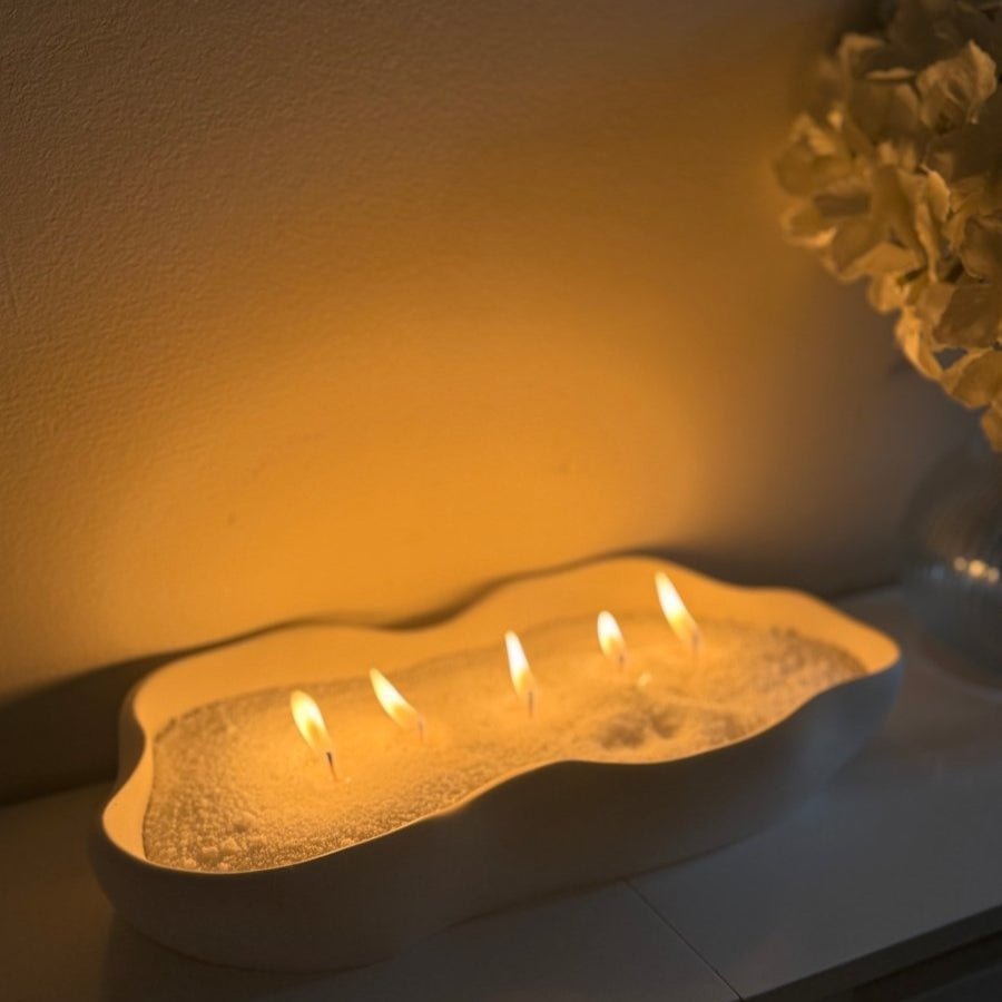 Irregular Stone container with candle sand wax lit emitting a soft warm glow on a neutral background