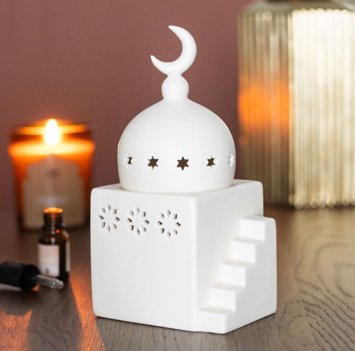 White ceramic diffuser with moon and star design on a wooden surface.