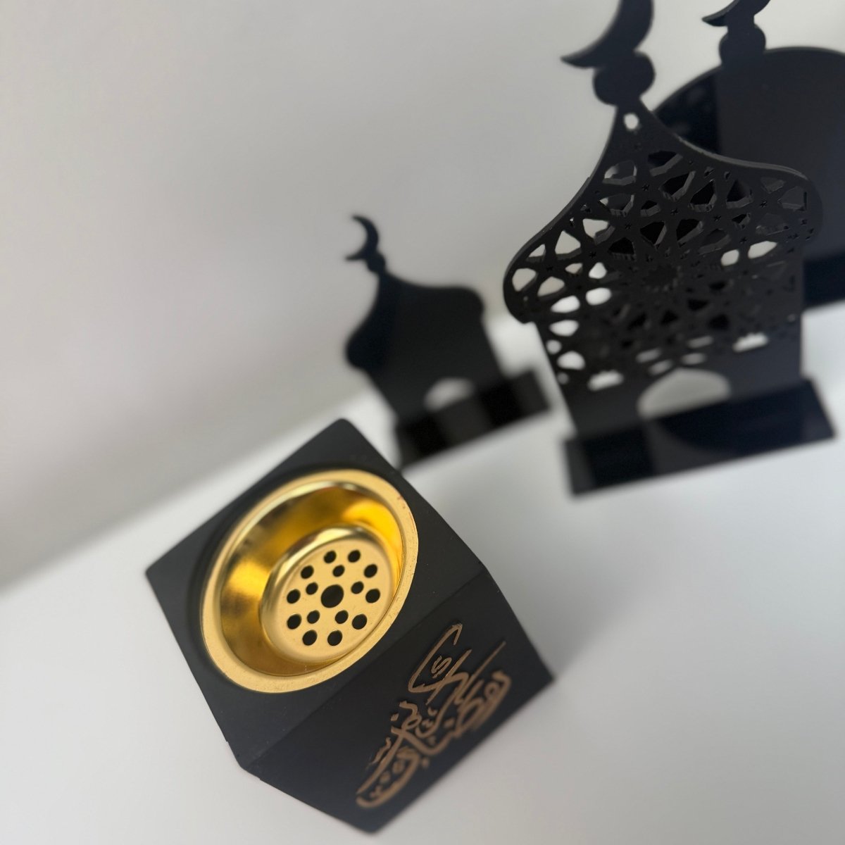 Black incense burner with gold interior on a white background