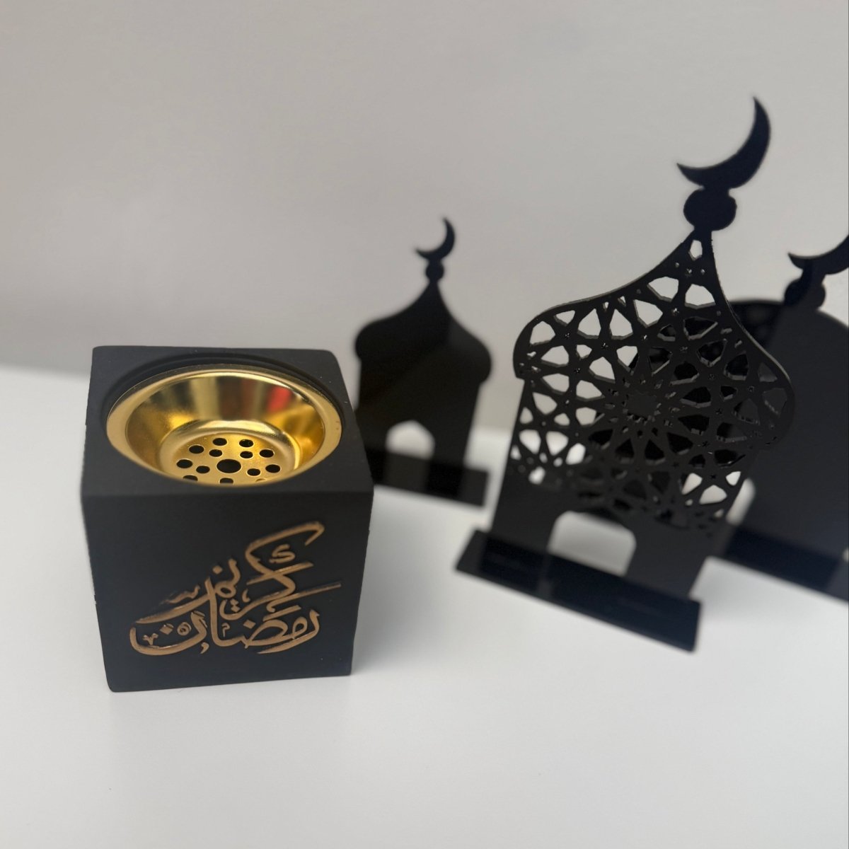 Black and gold incense burner with decorative stand on a white background