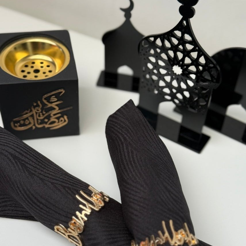 Black ribbons with gold text on a white surface, with black lanterns and a gold incense burner in the background.