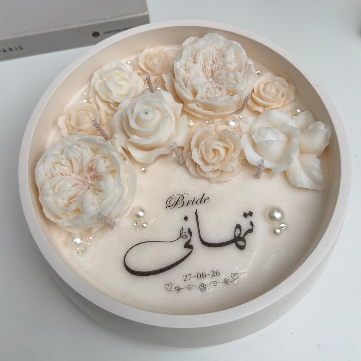 Decorative custom candle with white roses and Arabic text on a white background