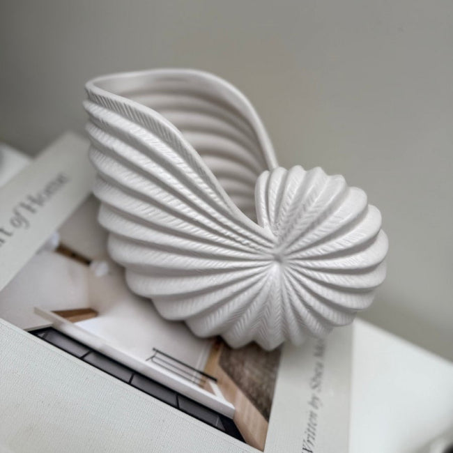 White Conch shell vase on a book with a gray background