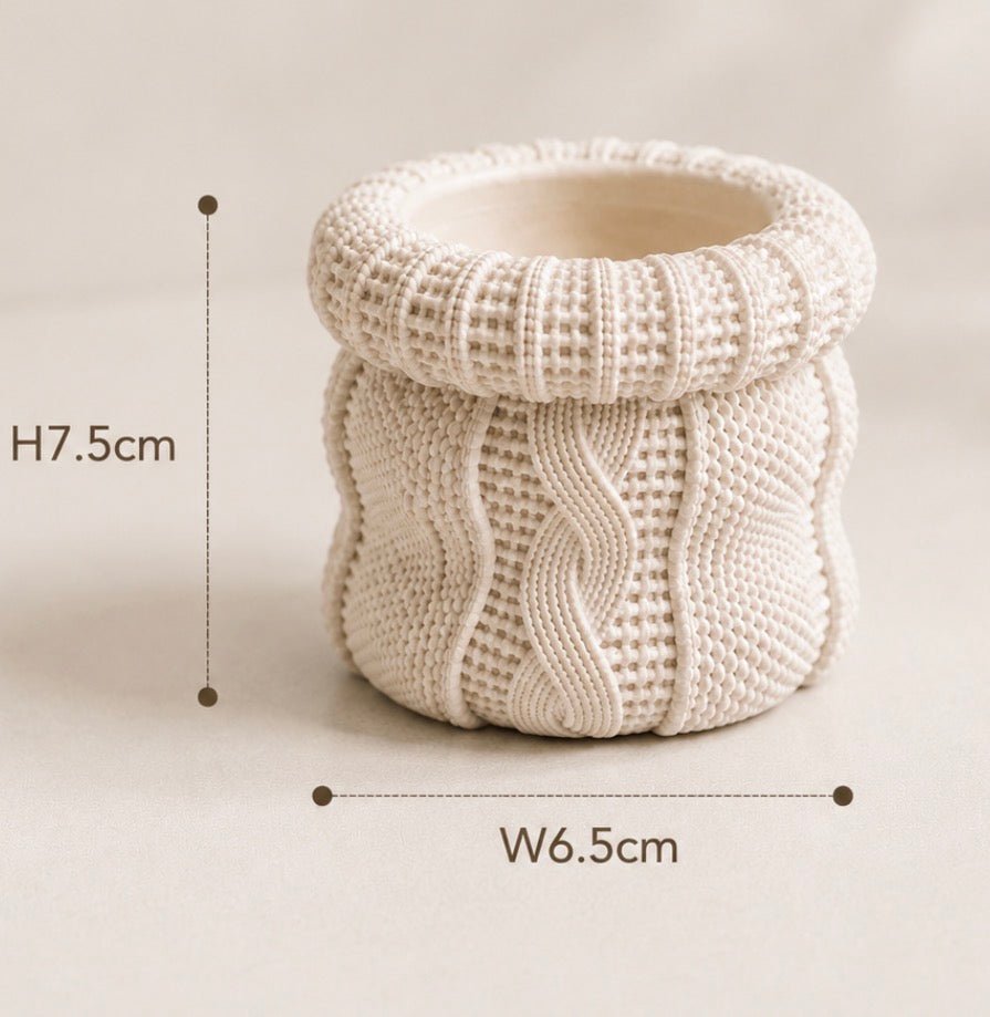 A cream-coloured knitted cylindrical container or candle holder with dimension markings showing a height of 7.5 cm and a width of 6.