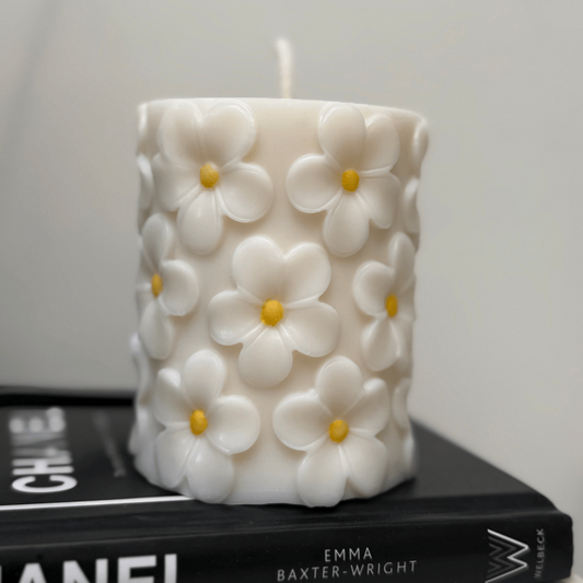 Decorative candle with floral design on top of books