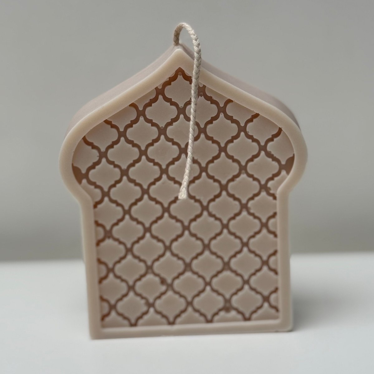 Decorative mosque dome-shaped candle with lattice design on a gray background