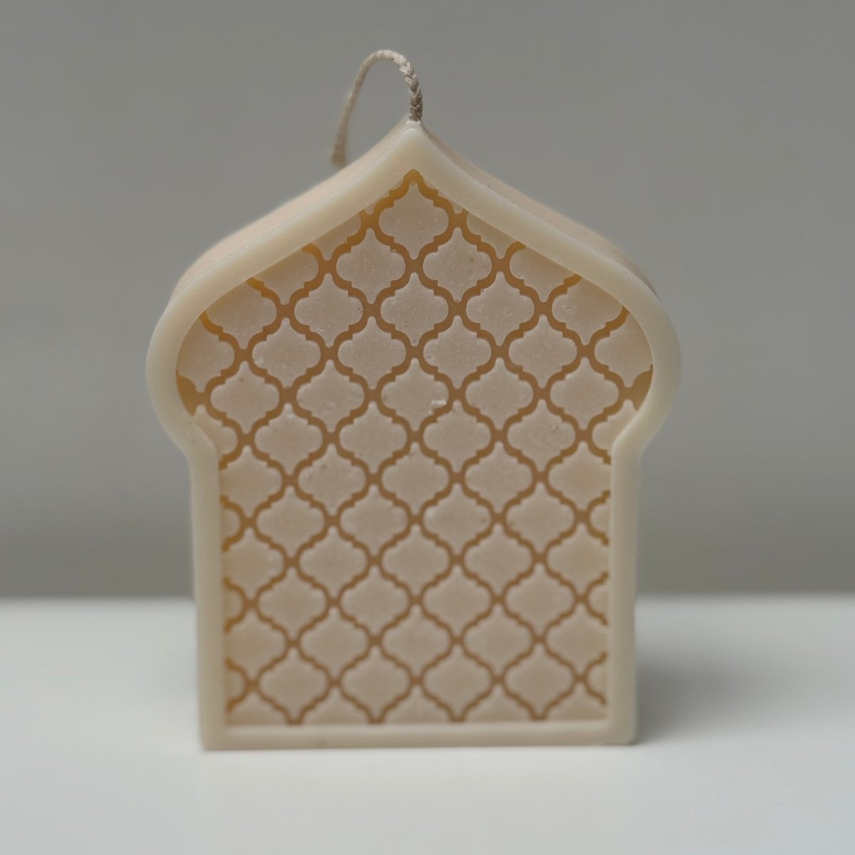 Decorative mosque dome-shaped candle with lattice design on a gray background