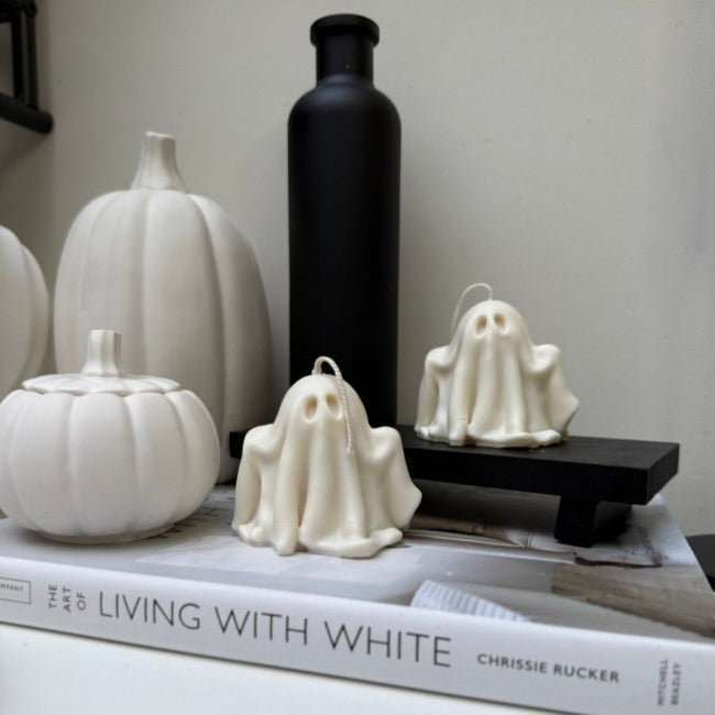 Decorative Ghost candles including white pumpkins  on a book titled 'Living with White' by Chrissie Rucker.