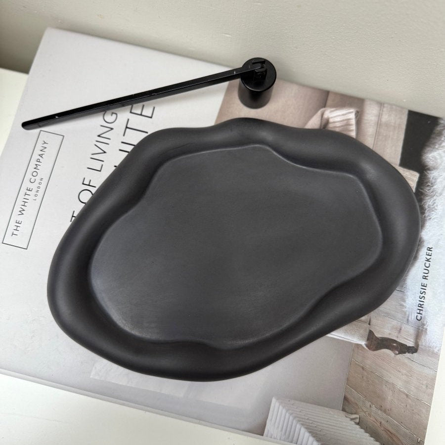 Black ceramic dish on a magazine with a pen on top