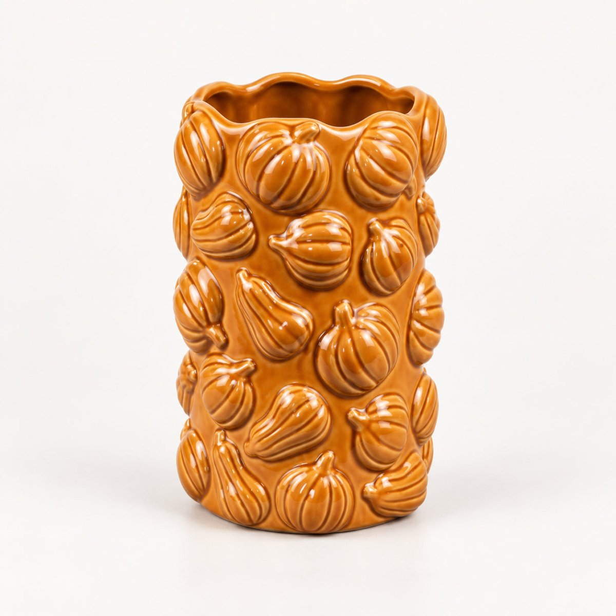 An orange glazed ceramic vase featuring a raised relief pattern of pumpkins and gourds, set against a plain white background.