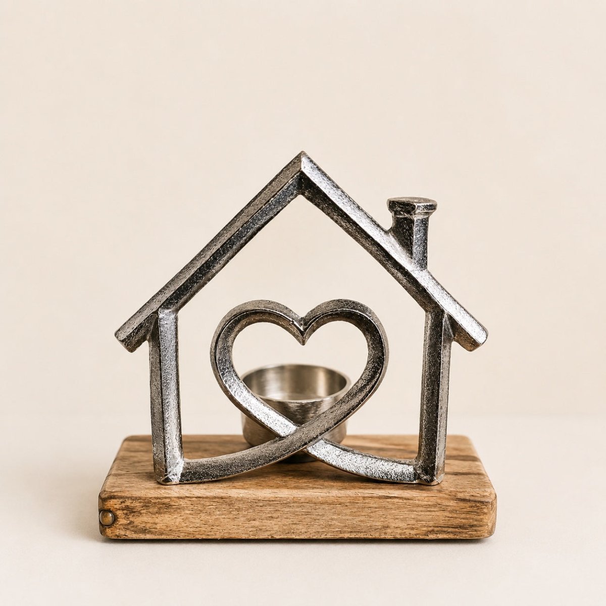 A rustic metal house-shaped candle holder with a heart motif in the center, mounted on a rectangular wooden base against a warm beige background.