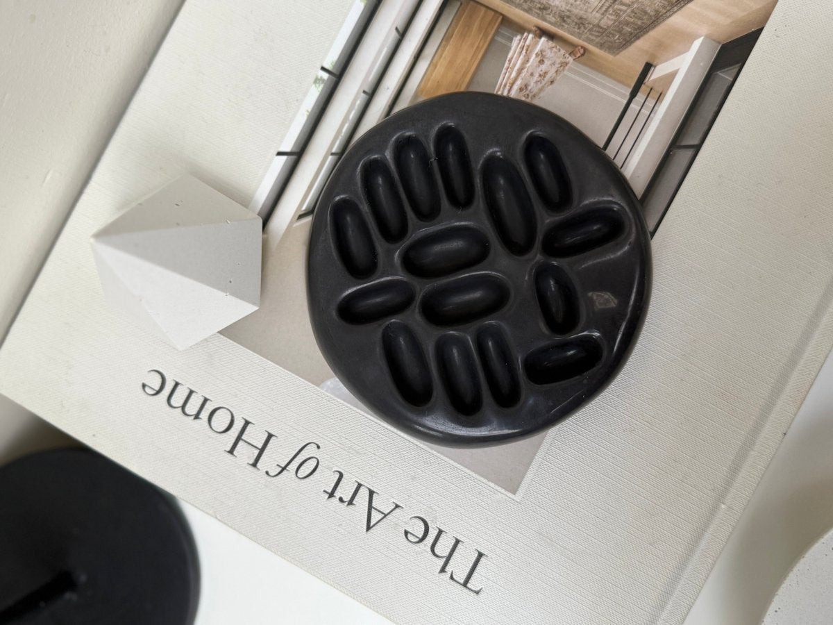 Black ceramic ring holder on a magazine with 'The Art of Home' branding.