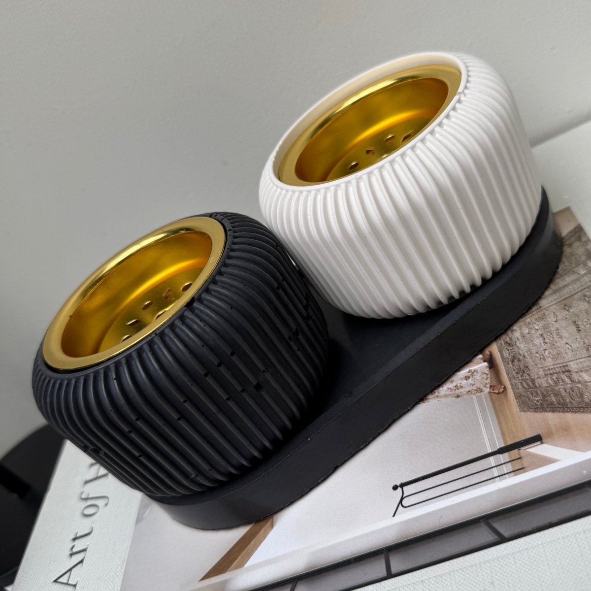 Modern stone Bakhoor incense burner in black and white with gold-tone plates on display.