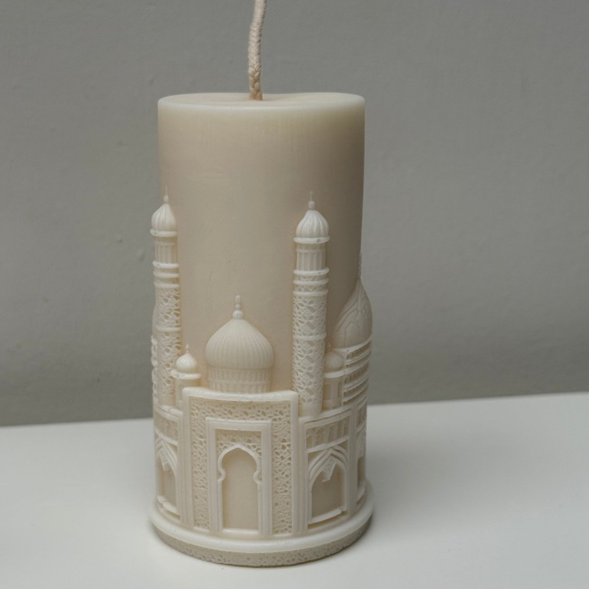 Decorative candle with architectural design on a plain background