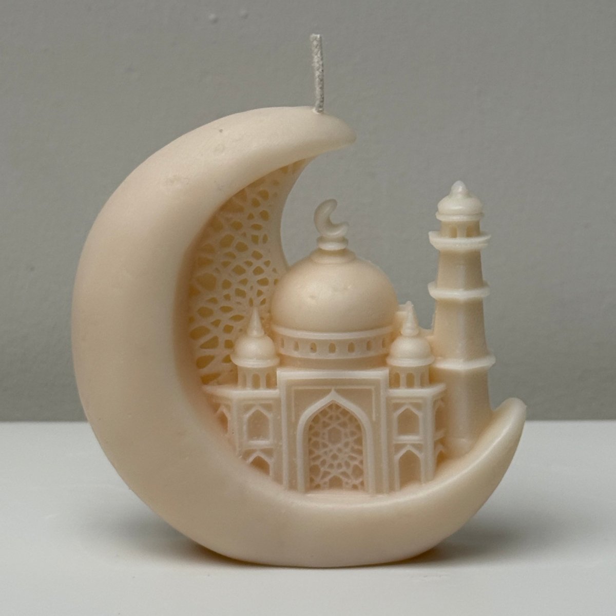Decorative crescent moon candle with intricate architectural design on a plain background