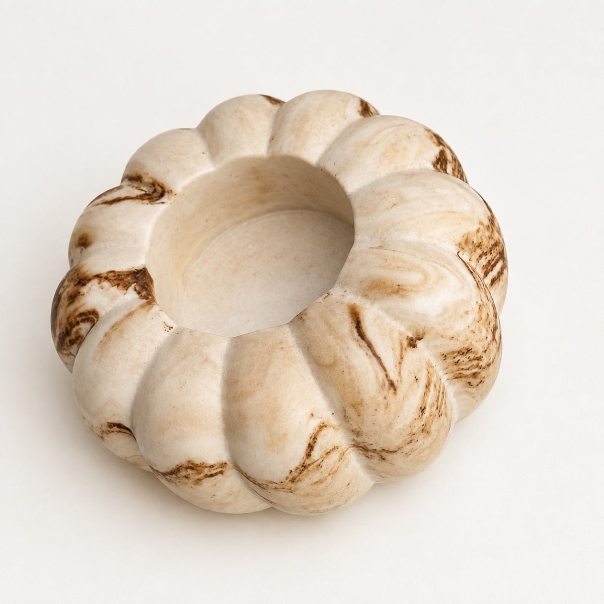A round stone pumpkin tealight candle holder, with a smooth surface , shown on a clean white background.