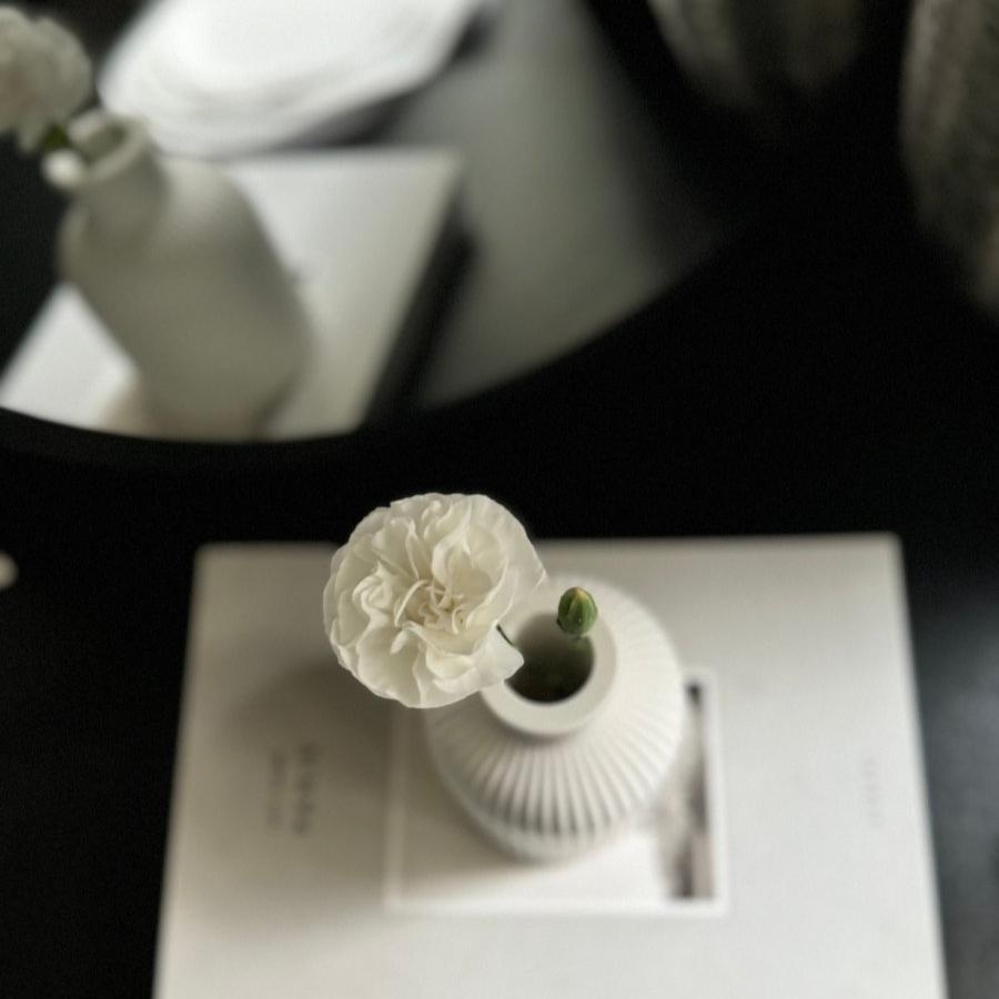 ORA Stone Vase styled on a minimalist living room coffee table with smail white flower inside it.