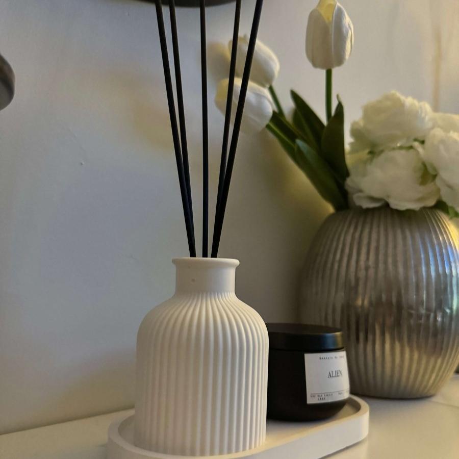 SORA Stone Vase styled on a minimalist living room side table next to a candle and silver container with white flowers
