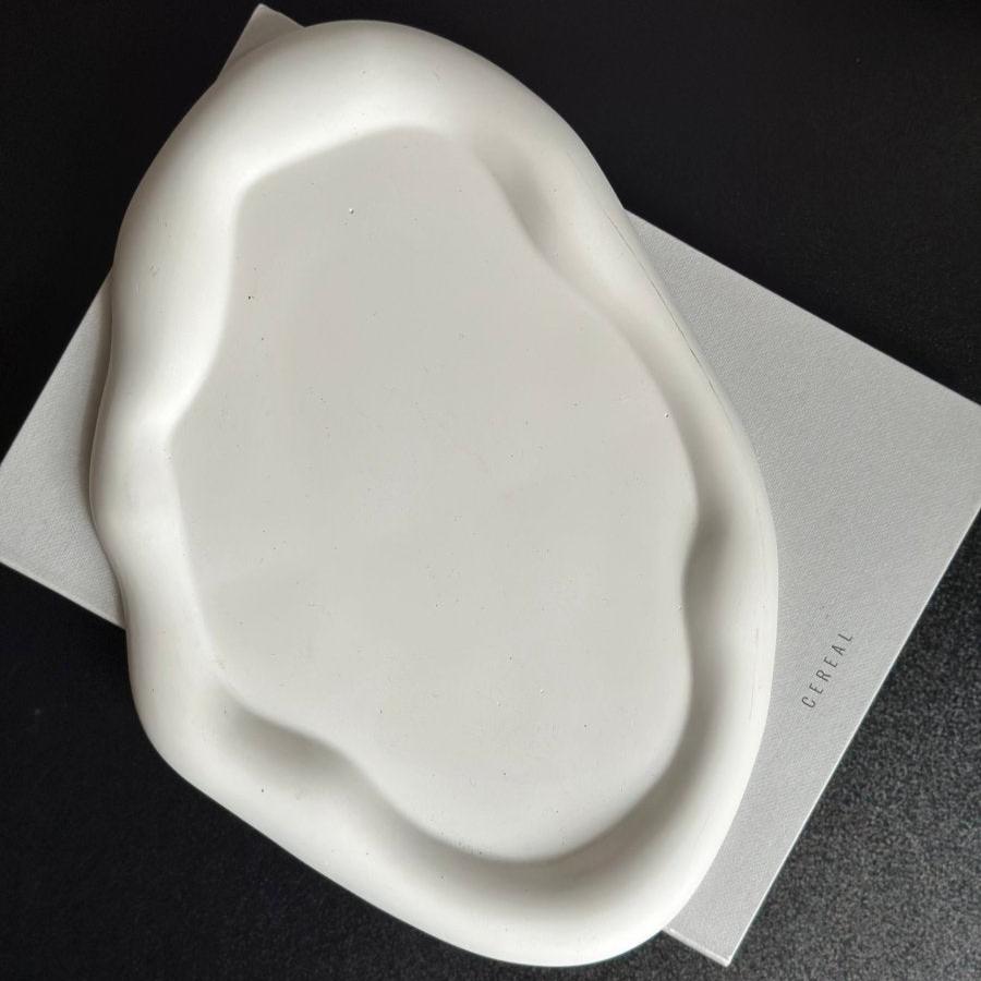 A handcrafted cloud-shaped stone decor tray on a white surface with a neutral color and minimalist design.