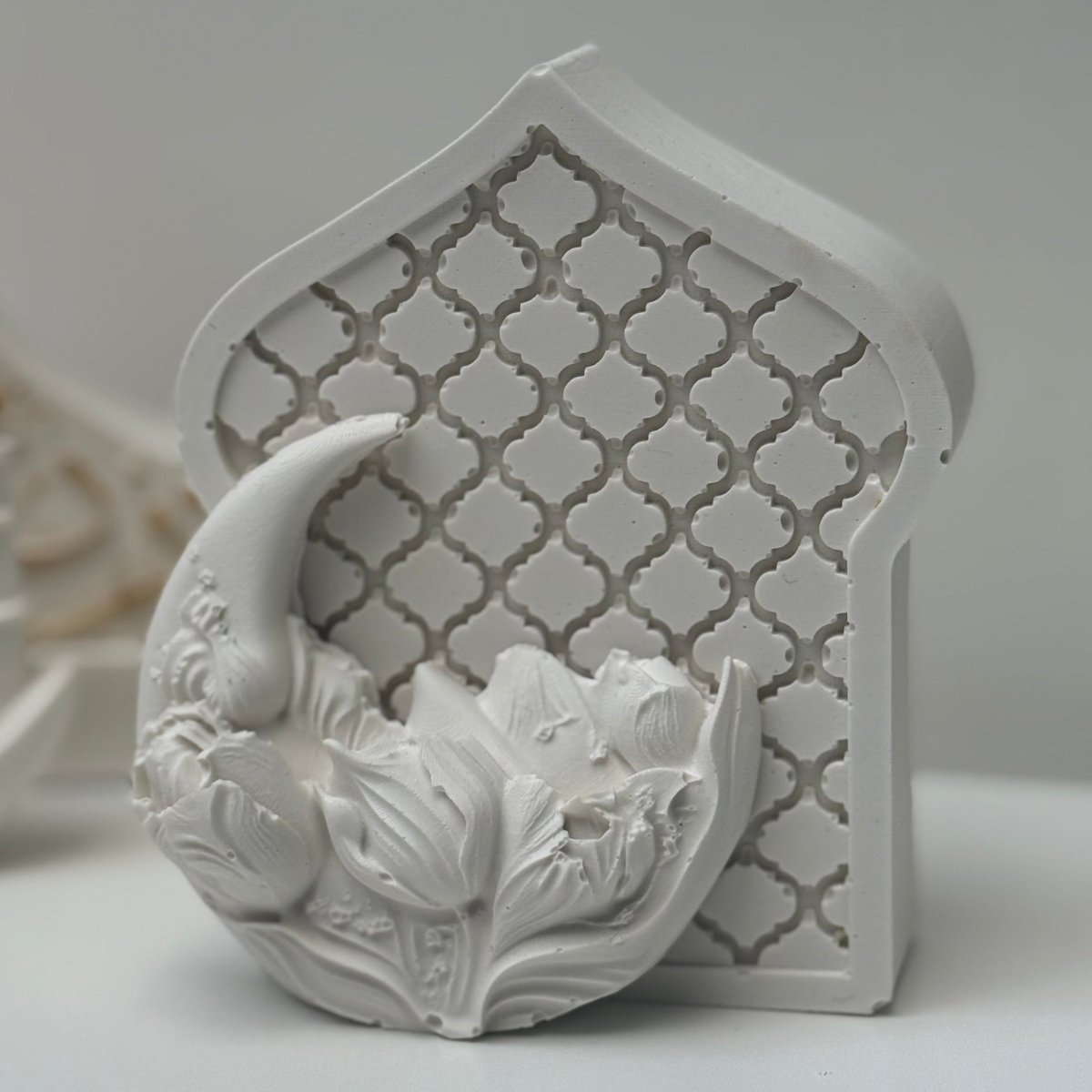 Decorative white ceramic piece with floral design on a light gray background