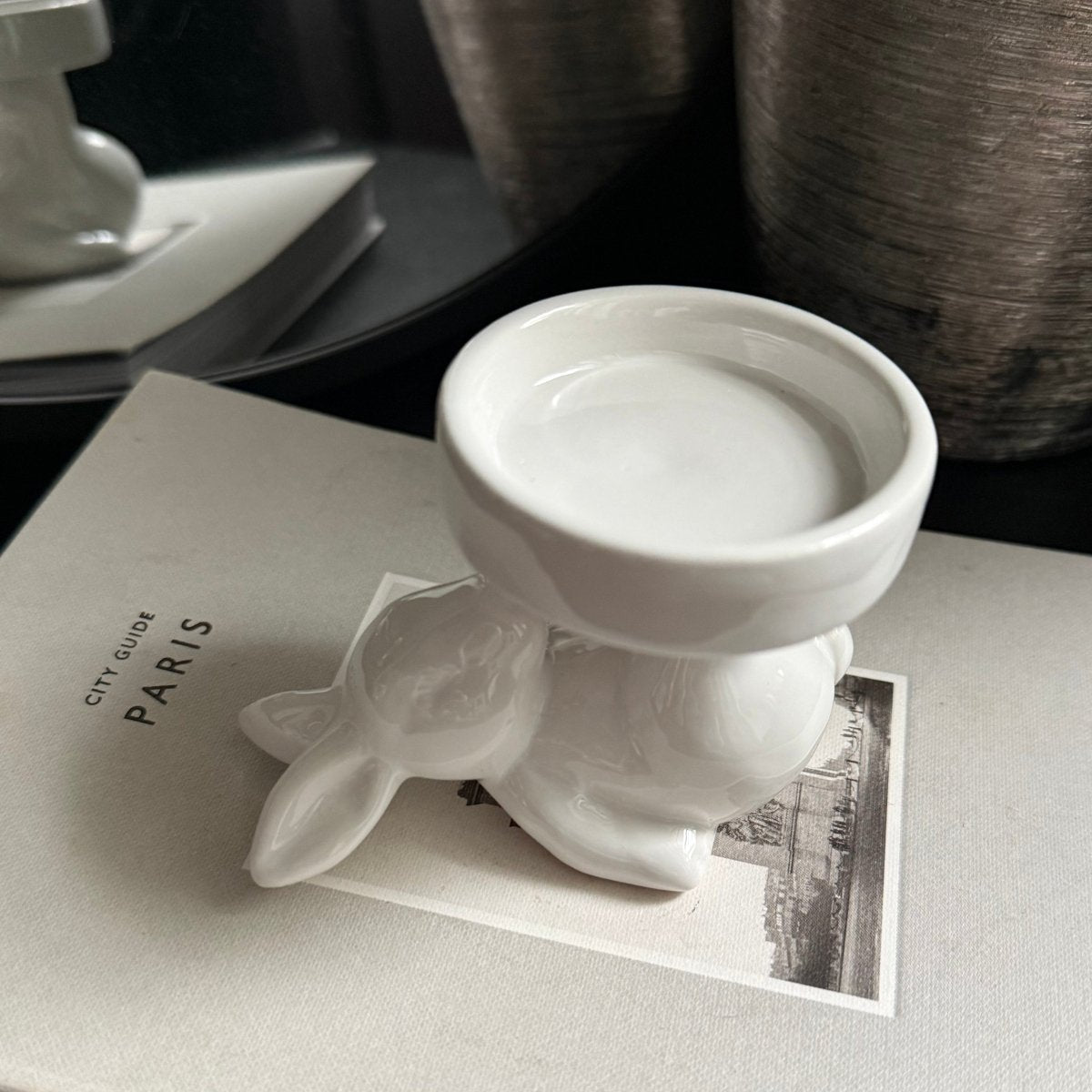White ceramic candle holder -sculpture of a rabbit on a textured surface with 'PARIS' branding.
