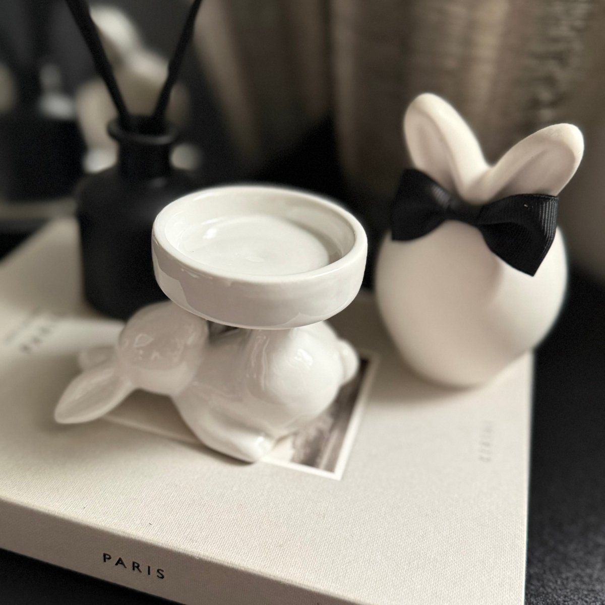 white ceramic rabbit candle holder - Decorative ceramic rabbit figurines with a black bow tie on a tray with 'PARIS' branding.