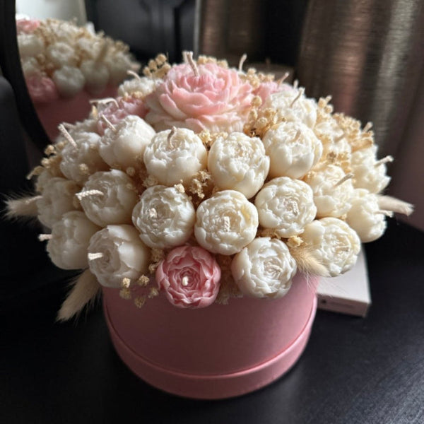 Decorative flower arrangement in a pink pot on a dark surface