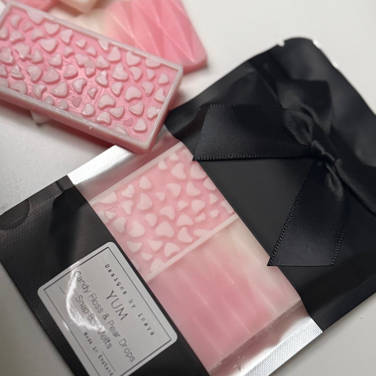 Candy floss and pear drops wax melt snap bars UK sweet scented wax melts, Pink wax melt snap bars with a black bow on a white background. 